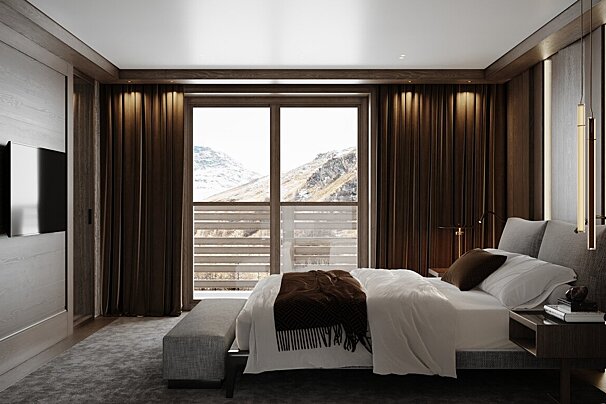 A stylish bedroom with dark wood accents, white bedding, and a large window overlooking a scenic, snowy mountain range.