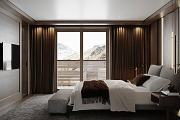 A stylish bedroom with dark wood accents, white bedding, and a large window overlooking a scenic, snowy mountain range.