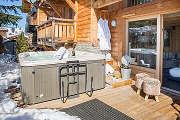 A hot tub sits outside of a wooden cabin