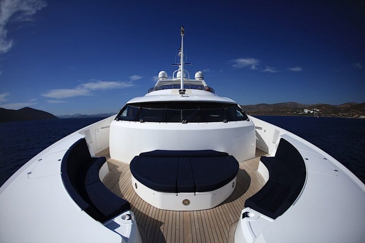 The front of a white yacht with mountains in the background