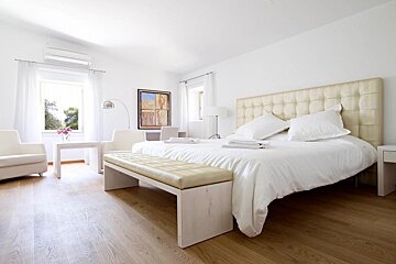 A bedroom with a large bed and a bench
