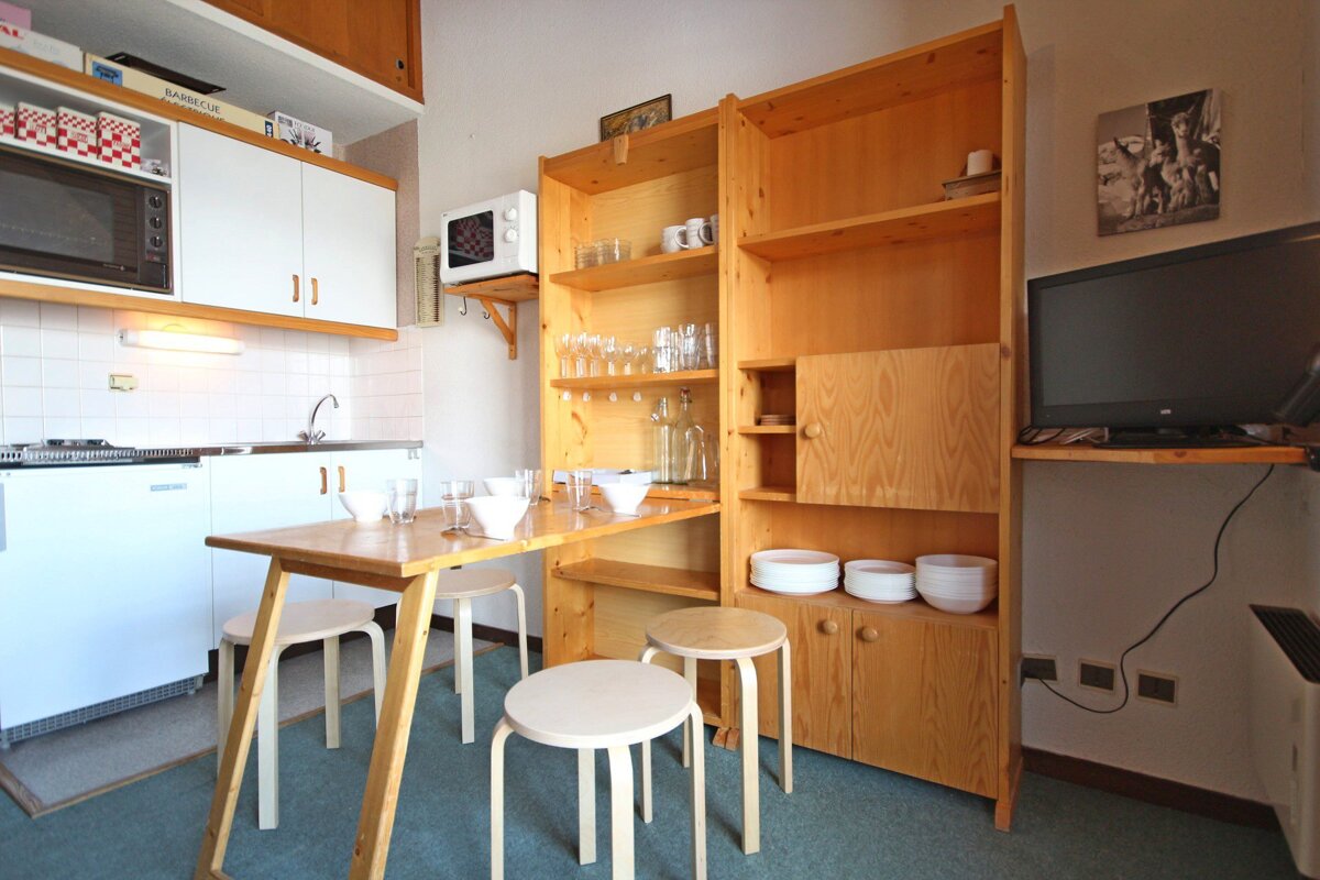 A small kitchen with a table and stools and a microwave