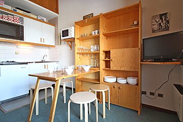 A small kitchen with a table and stools and a microwave