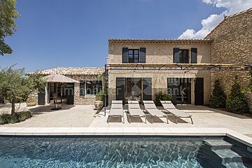 A large stone house with a swimming pool in front of it
