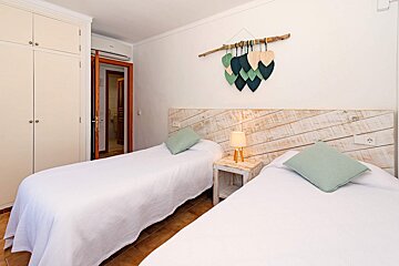 A bedroom with two beds and a wooden headboard