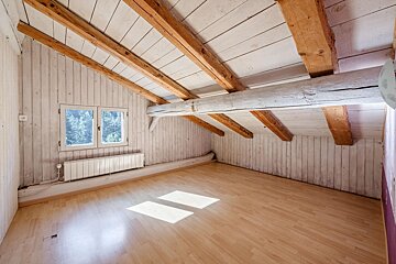 An empty room with wooden beams and a window