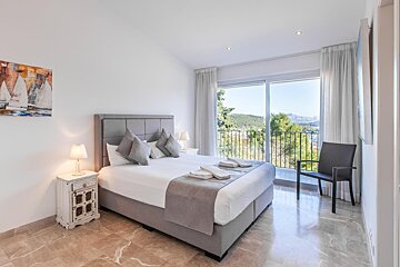A bedroom with a painting of sailboats on the wall above the bed