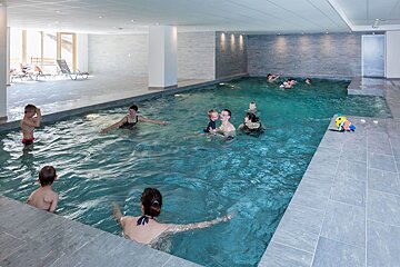 A group of people are swimming in a large indoor pool