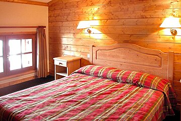 A bedroom with a bed and two lamps on the wall