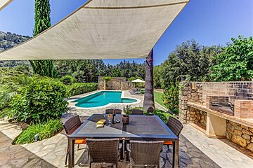 A patio with a table and chairs in front of a swimming pool