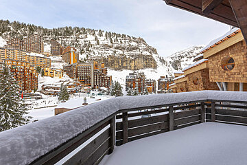 A balcony with a view of a ski resort covered in snow