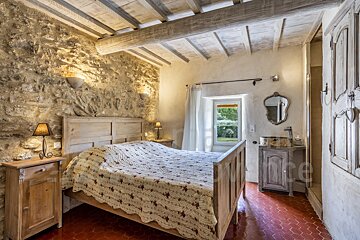 A bedroom with a wooden bed and a stone wall