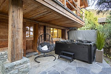 A black hot tub sits outside of a wooden building
