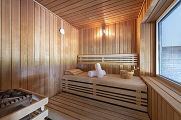 A wooden sauna with towels and a bucket on the bench