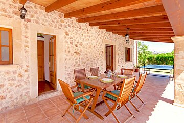 A patio with a table and chairs under a wooden roof