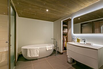 A bedroom with a bed and two lamps on the wall