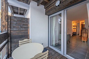 A balcony with a table and chairs and a sliding glass door