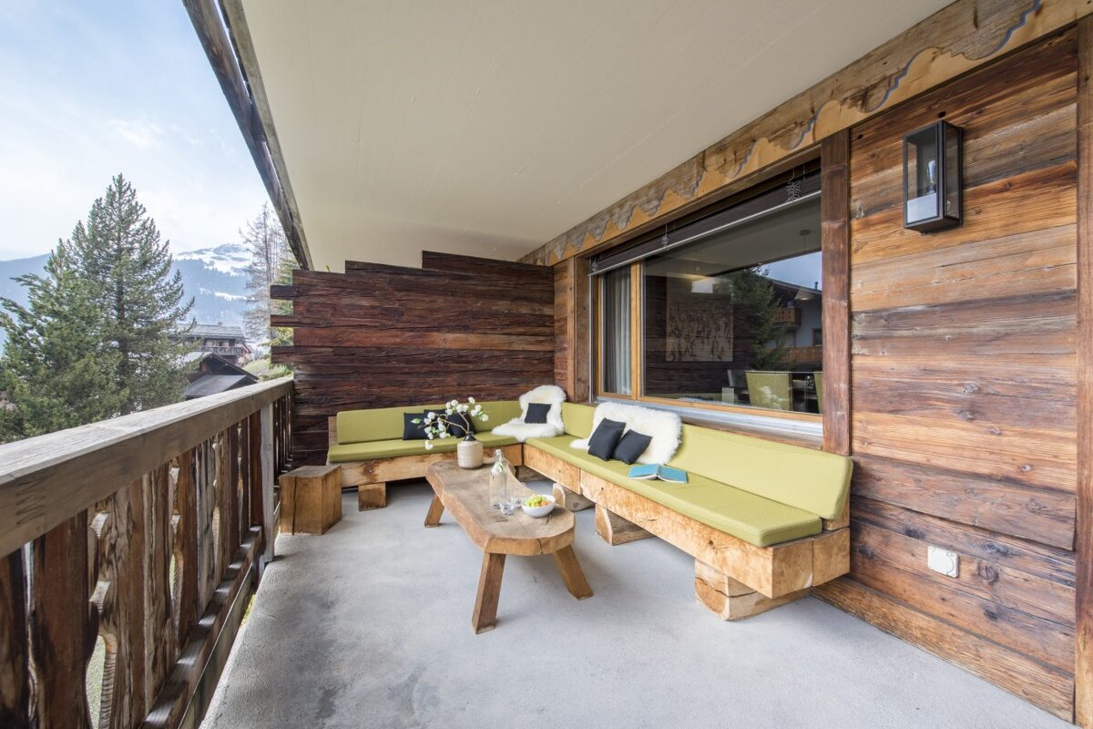 A wooden balcony with a couch and a table