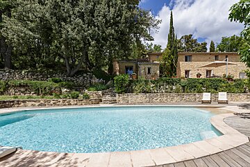 A large swimming pool in front of a stone house