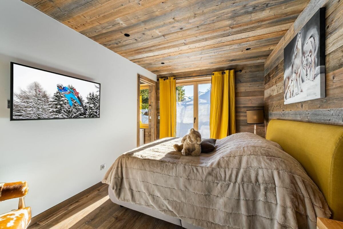 A bedroom with a bed and a television on the wall