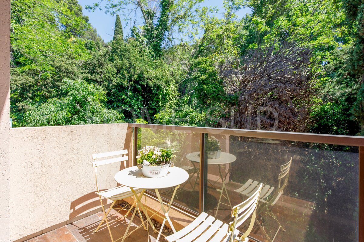A balcony with a table and chairs and a potted plant that says ' fleurs ' on it