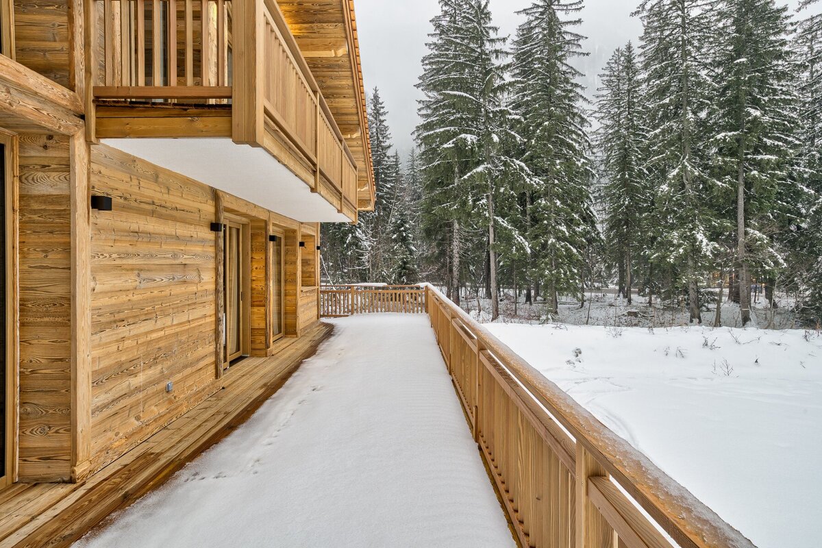 A wooden house with snow on the ground and trees in the background