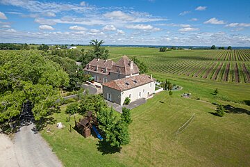 A large house sits in the middle of a lush green field