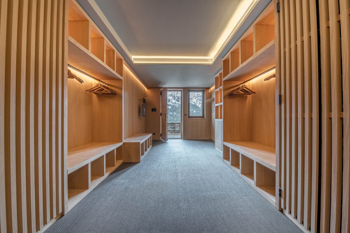 A walk in closet with wooden shelves and benches
