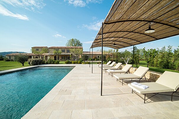 A row of lounge chairs under an umbrella next to a swimming pool