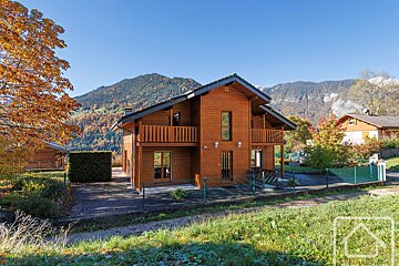 A large wooden house with mountains in the background