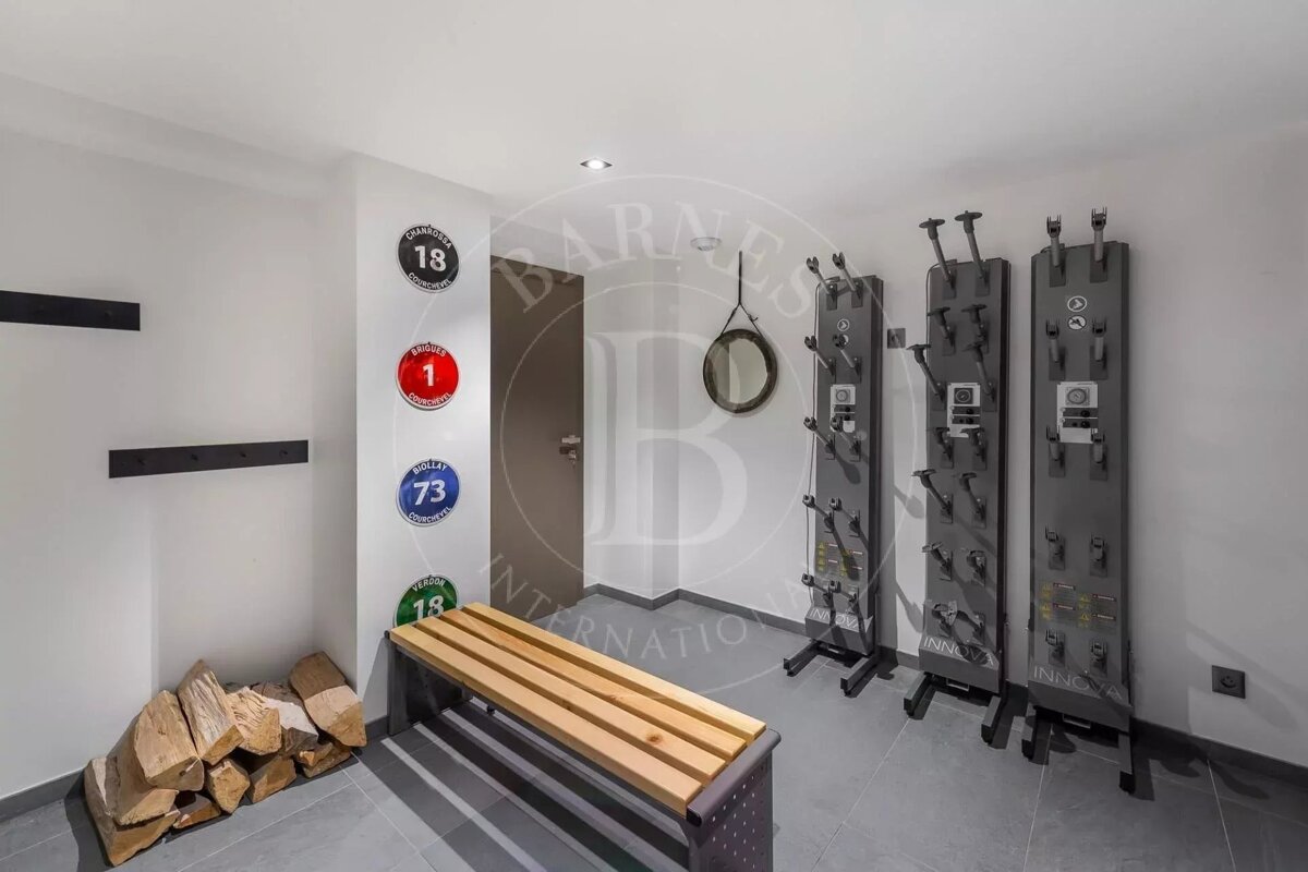 A modern ski room with Innovair boot dryers, a wooden bench, stacked firewood, and ski resort-themed wall decor. Ready for winter sports.