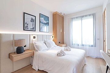 A bedroom with a large bed and two paintings on the wall