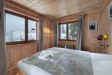 A bedroom with a bed and a window with snow on the trees