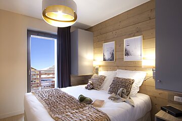 A bedroom with a bed and two pictures on the wall