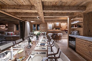 A dining room table with a bottle of wine on it