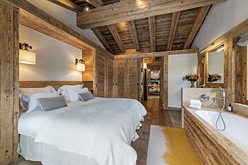 A bedroom with a large bed and a bathtub