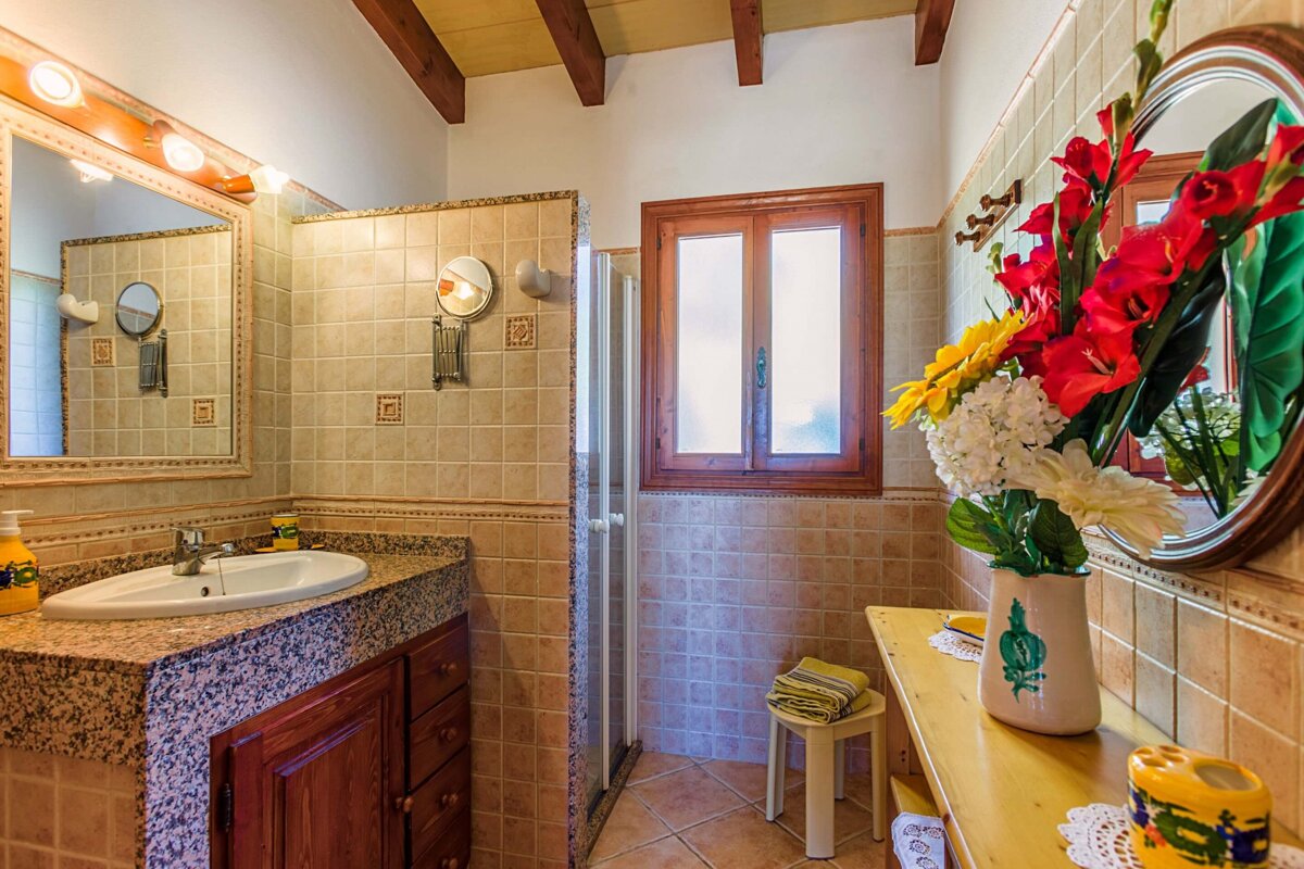 A bathroom with a sink a mirror and a vase of flowers