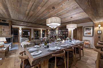 A dining room table with a bottle of wine on it