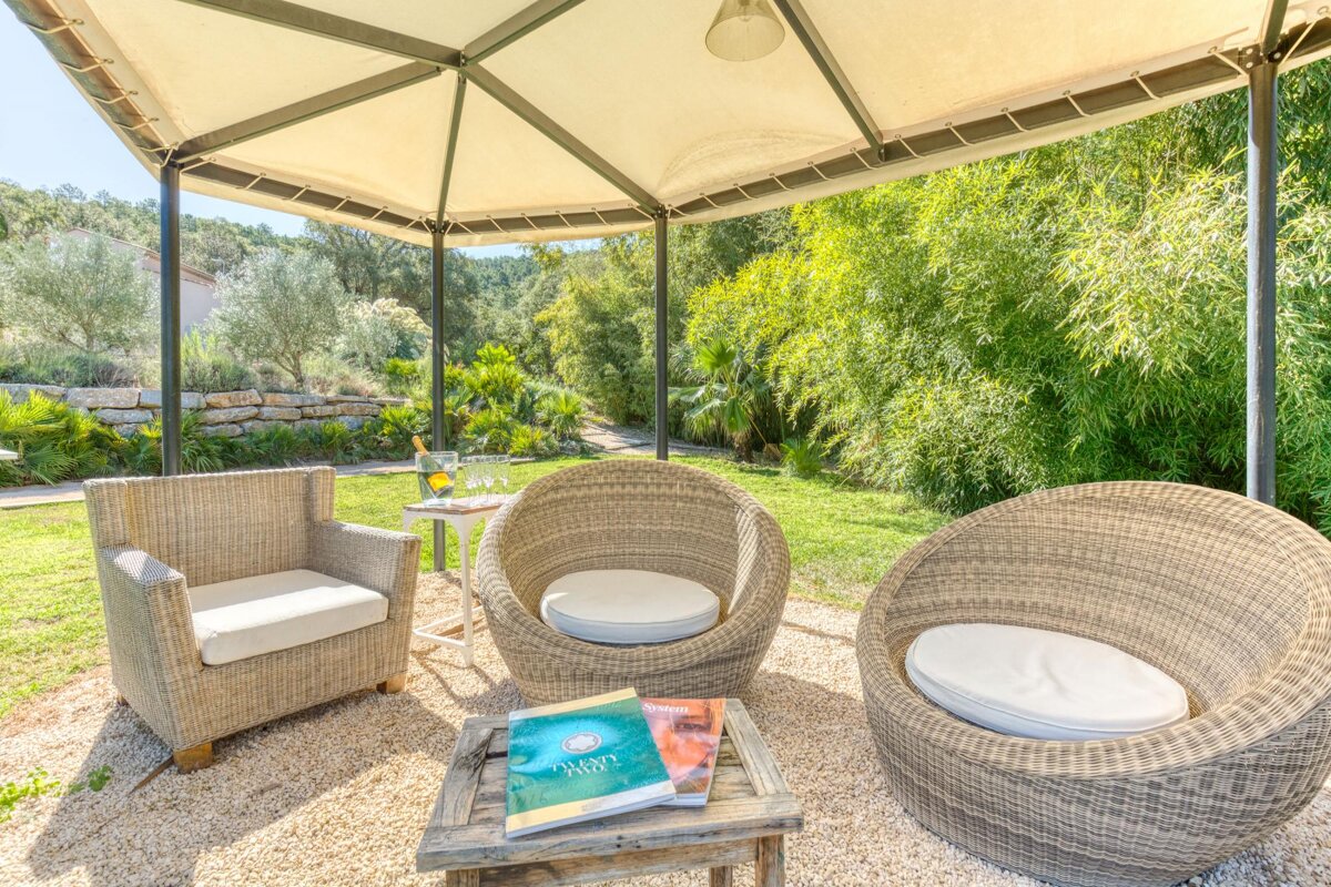 Two wicker chairs under a gazebo with a book on a table that says yoga