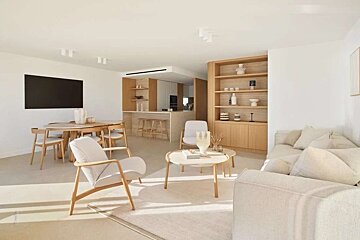 Bright, modern open-plan living space with dining and kitchen areas. Features light wood furniture, neutral tones, and minimalist decor.
