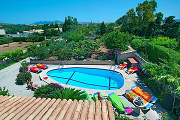 A large oval shaped swimming pool surrounded by chairs and plants