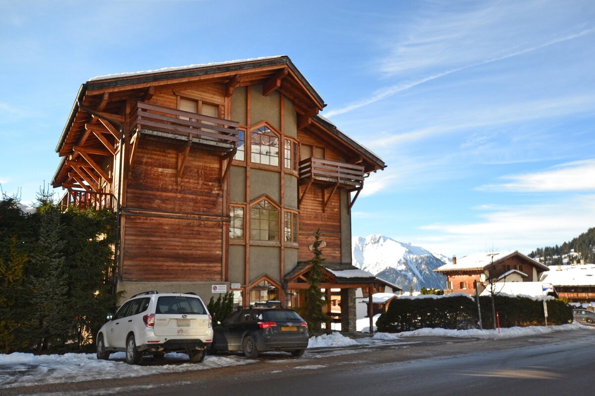 A white suv is parked in front of a wooden building
