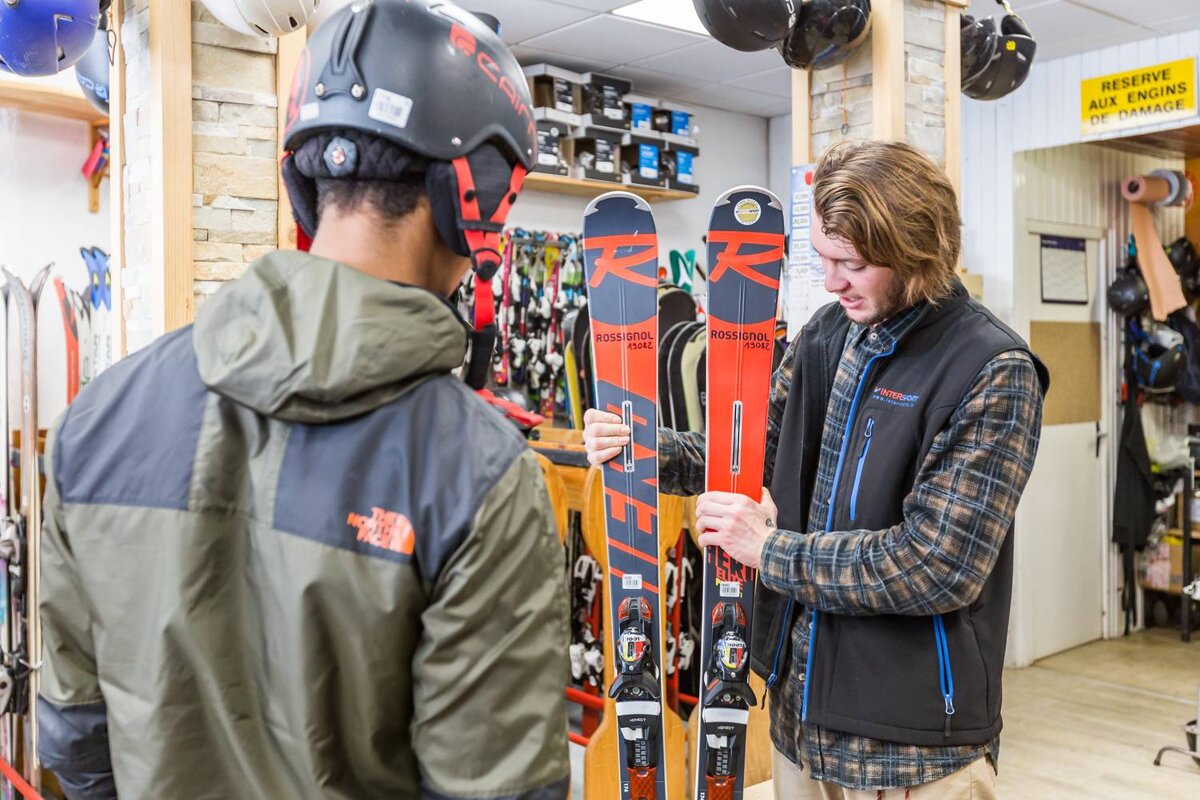 A man holding a pair of skis that say rossignol on them
