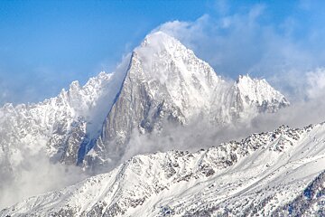 A snowy mountain with a blue sky in the background