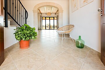 A wicker chair sits in a hallway next to a potted plant