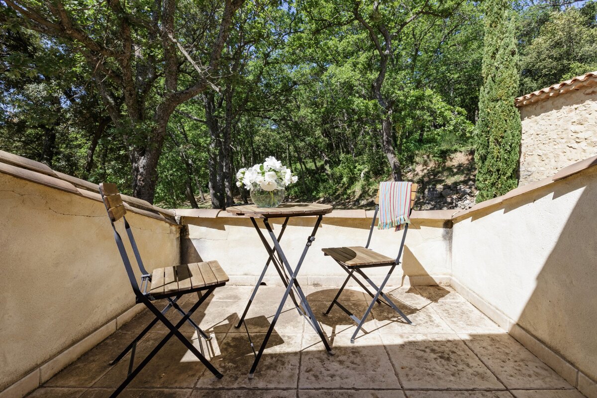 A table and chairs on a balcony with trees in the background