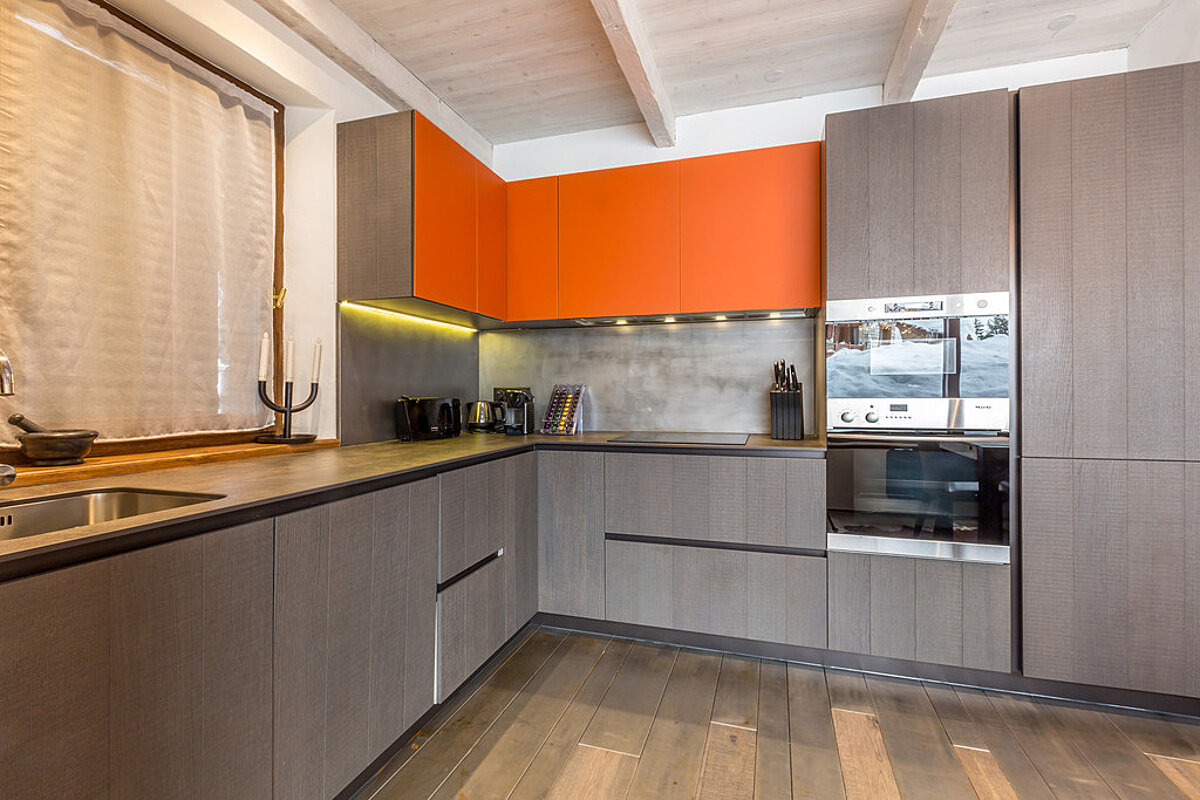 A kitchen with orange cabinets and stainless steel appliances