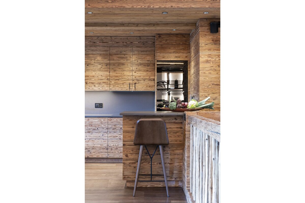 A kitchen with wooden cabinets and a wooden stool