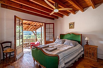 A bedroom with a green bed and a ceiling fan