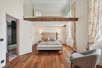 A bedroom with a large bed and a chair